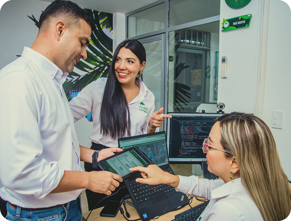 Fotografía de tres colaboradores de Ciudad Limpia reunidos en un entorno de oficina. Todos portan camisas blancas y cuentan con equipos de cómputo. Al fondo se aprecia una puerta de vidrio un mural con hojas verdes que ambienta la oficina.