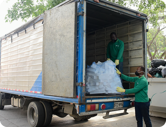 Dos colaboradores de Ciudad Limpia cargan material en la parte trasera de un camión, durante una jornada de recolección y manejo de residuos.
