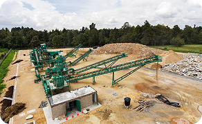 Vista general de una planta con bandas transportadoras y zonas de acopio de materiales, en un entorno abierto rodeado de vegetación.
